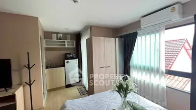 Modern bedroom with kitchenette and large window offering natural light.