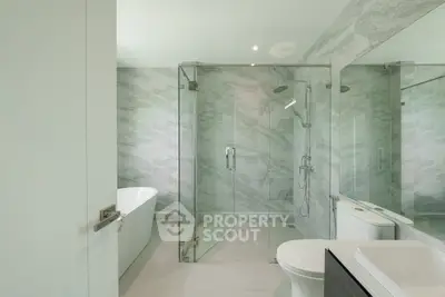 Luxurious modern bathroom with marble walls and glass shower enclosure.