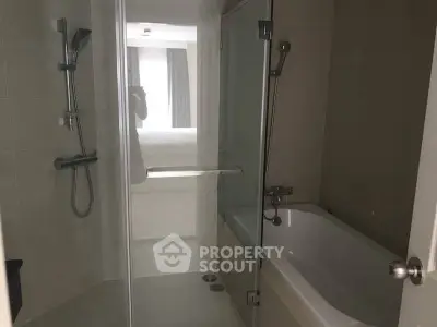 Modern bathroom with glass shower and bathtub in sleek apartment.