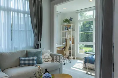 Bright living room with cozy seating and study area overlooking lush garden views.