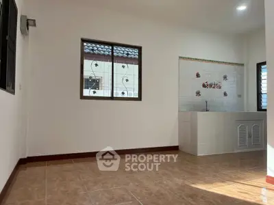 Spacious room with tiled floor and kitchen area, perfect for modern living.