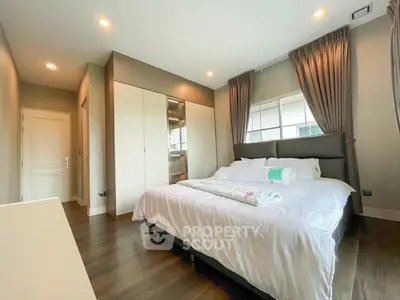 Spacious bedroom with elegant decor and ample natural light, featuring a large bed and built-in wardrobe.