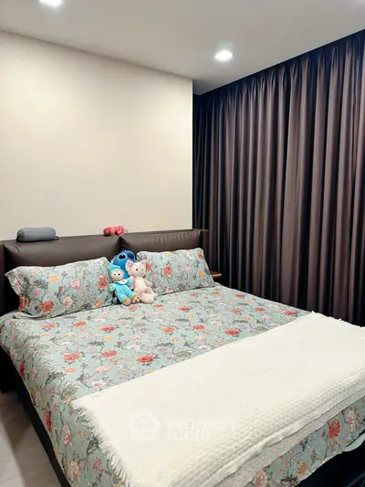 Cozy bedroom with floral bedding and plush toys, perfect for relaxation.