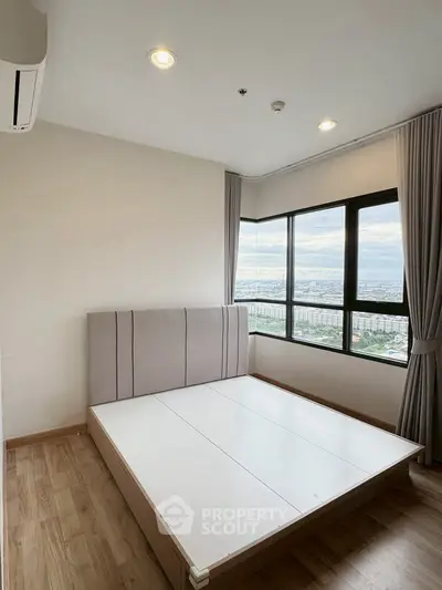 Spacious bedroom with large windows offering stunning city views, featuring modern design and ample natural light.