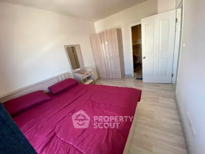 Spacious bedroom with modern furniture and vibrant red bedding, perfect for a cozy retreat.