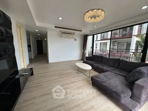 Spacious modern living room with large windows and elegant chandelier