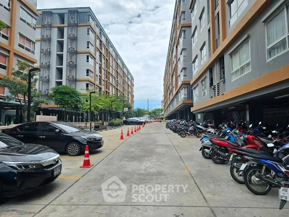 Modern apartment complex with parking area and motorbikes, showcasing urban living convenience.