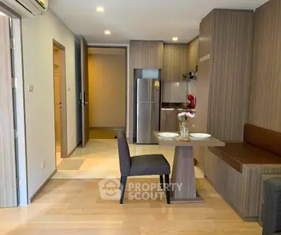 Modern kitchen with dining area in stylish apartment, featuring wood cabinetry and stainless steel appliances.