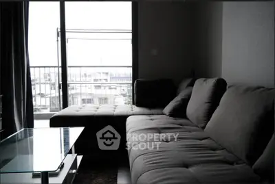 Modern living room with plush gray sectional sofa and glass coffee table, offering a cozy ambiance and city view.
