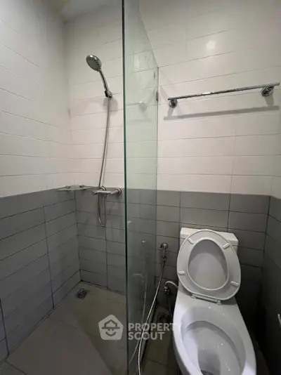 Modern bathroom with shower and toilet in sleek gray and white tiles.