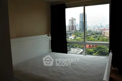 Spacious bedroom with large window offering stunning cityscape views in modern apartment.