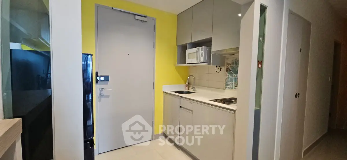 Modern compact kitchen with sleek cabinetry and built-in appliances in a stylish apartment.