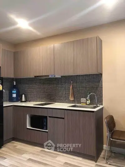 Modern kitchen with sleek cabinetry and stylish backsplash in a cozy apartment.