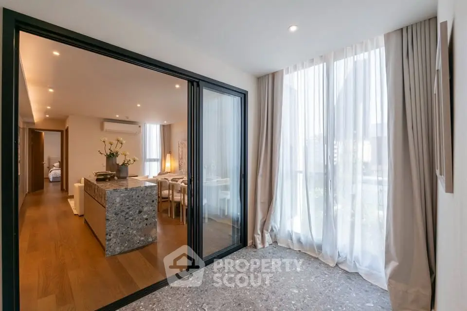 Modern open-plan living and dining area with floor-to-ceiling windows and elegant decor.