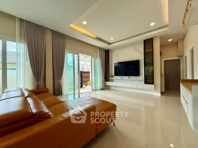 Spacious modern living room with leather sofa and large TV, perfect for relaxation.