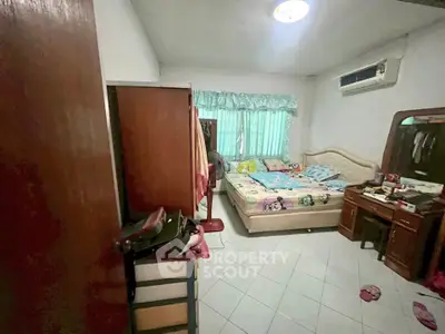 Cozy bedroom with air conditioning and natural light, featuring a comfortable bed and wooden furniture.
