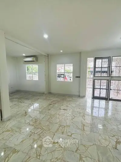 Spacious marble-floored living room with large windows and natural light