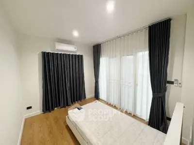 Spacious bedroom with large windows and elegant curtains, featuring a minimalist design.