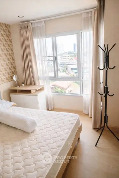 Bright and cozy bedroom with large window offering city views, featuring modern decor and ample natural light.