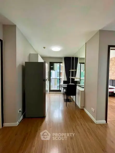 Modern apartment interior with wooden flooring and balcony view, featuring a compact dining area and mirrored wall.