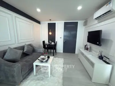 Modern living room with elegant decor, featuring a plush gray sofa, sleek white furniture, and ambient lighting.