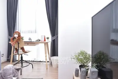 Modern living room with stylish decor and large TV, featuring a cozy workspace by the window.