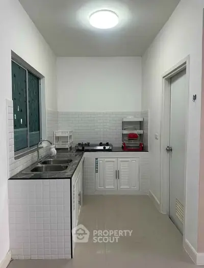 Modern kitchen with sleek white cabinetry and gas stove in a compact layout.