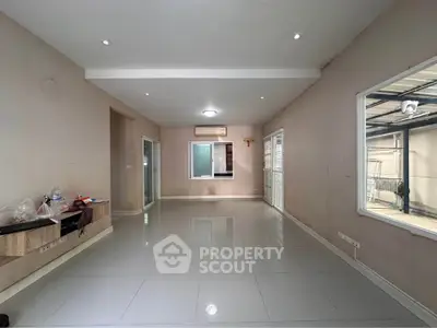 Spacious living room with modern tile flooring and large windows for natural light.