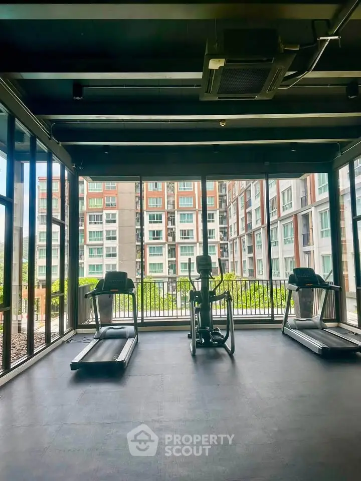Modern gym with large windows offering a view of the surrounding residential buildings.