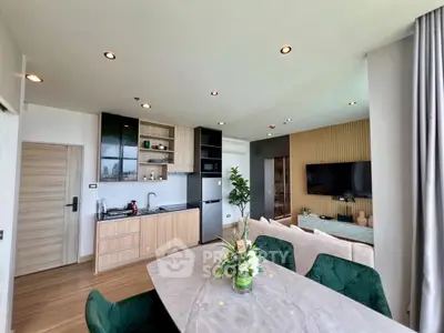 Modern open-plan living room with stylish kitchen and dining area, featuring elegant decor and natural light.