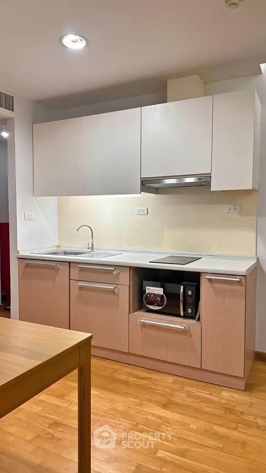Modern kitchen with sleek cabinetry and built-in appliances in a cozy apartment.
