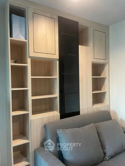 Modern living room with stylish built-in wooden shelving and cozy gray sofa.
