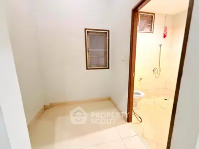 Spacious bathroom with tiled floor and shower area in modern apartment.