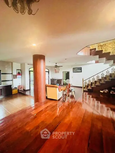 Spacious living room with wooden flooring and elegant staircase in a modern home.