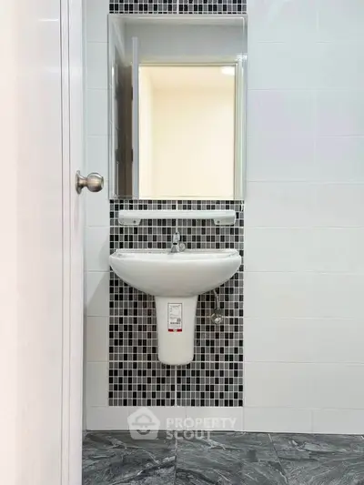 Modern bathroom with stylish mosaic tiles and sleek pedestal sink.