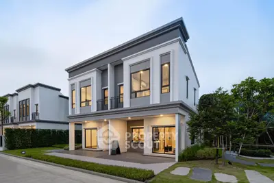 Modern two-story house with large windows and manicured lawn in a suburban neighborhood.