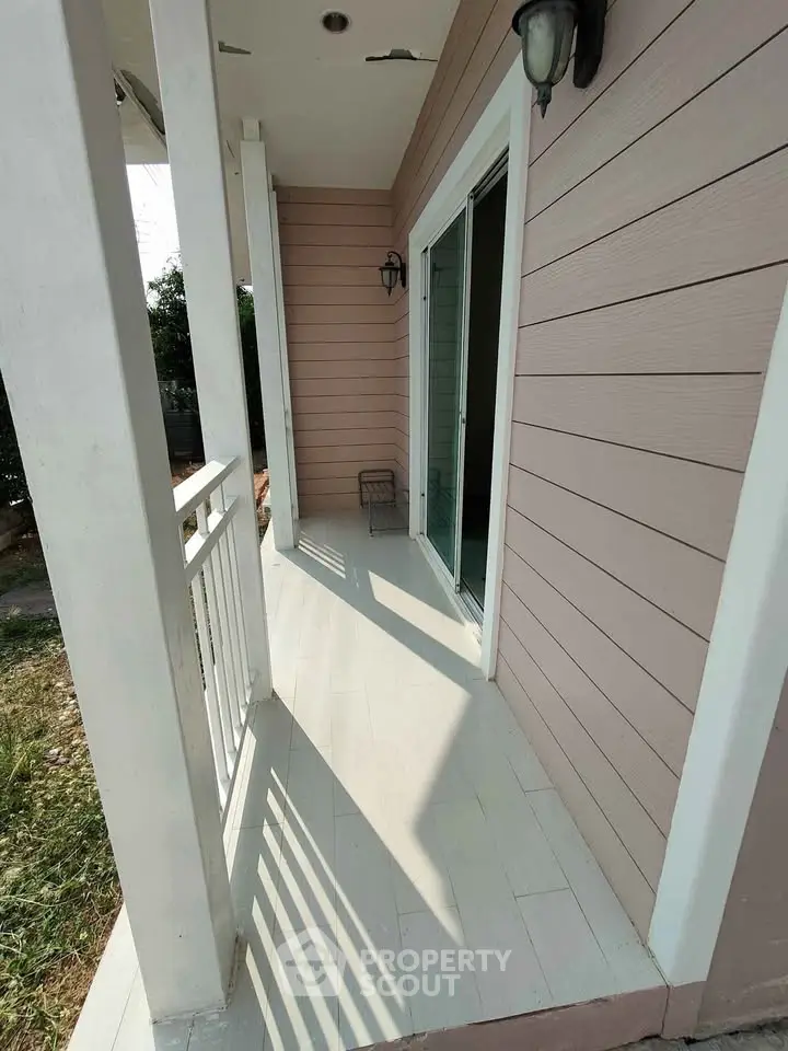 Charming small balcony with white railing and pink siding, perfect for relaxing outdoors.