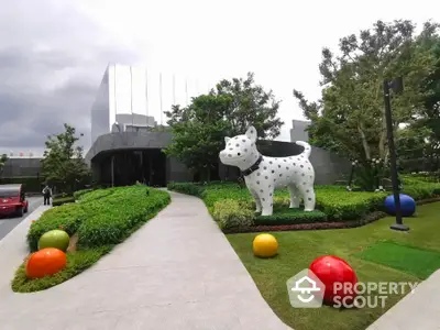 Modern building entrance with artistic dog sculpture and vibrant landscaping