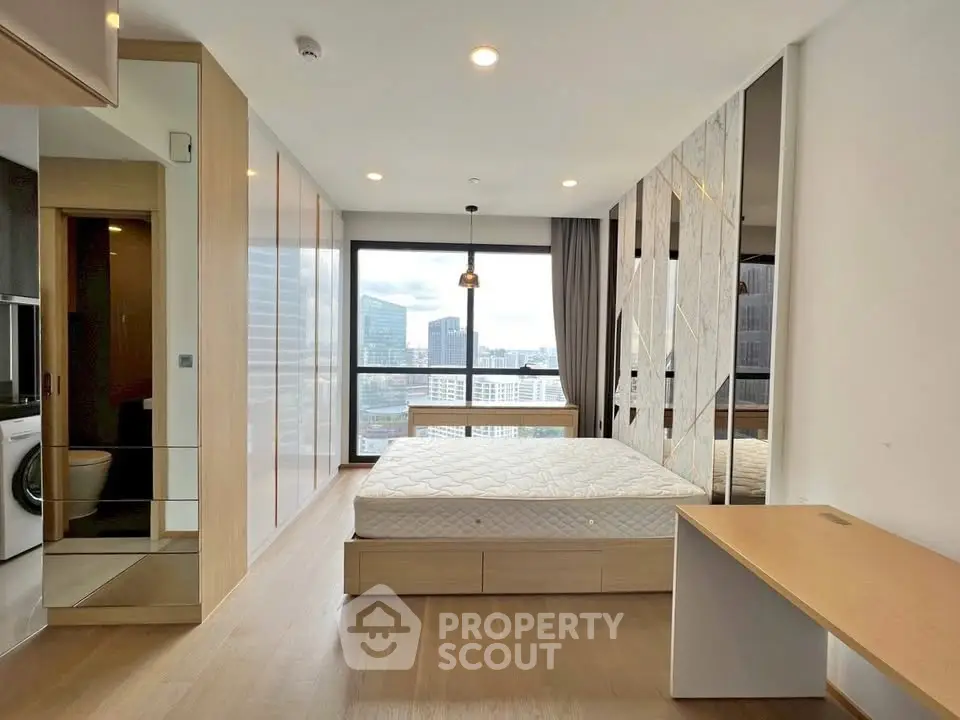 Modern bedroom with city view, featuring a large window, stylish decor, and ample natural light.