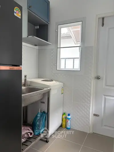 Compact kitchen with modern appliances and sleek design, featuring a washing machine and ample storage space.