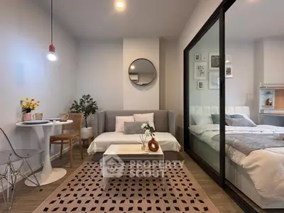 Modern studio apartment with cozy living area and stylish bedroom separated by glass partition.