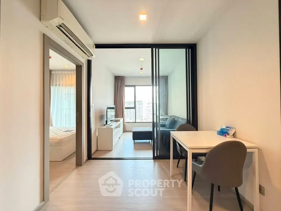 Modern apartment interior with open living and dining area, featuring large windows and stylish furniture.