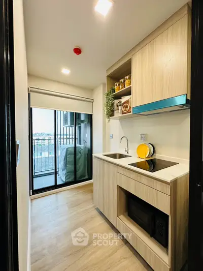 Modern kitchen with sleek cabinetry and balcony view, featuring an open layout and contemporary appliances.