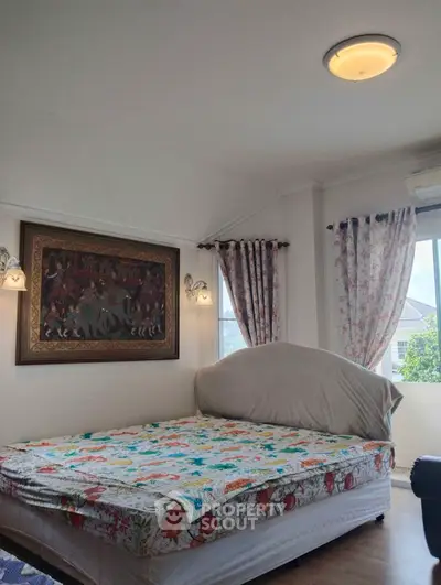 Spacious bedroom with large windows, elegant curtains, and a comfortable king-size bed, adorned with a classic painting and warm lighting.