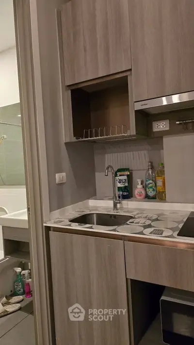 Modern compact kitchen with sleek cabinetry and built-in appliances, adjacent to a bathroom.