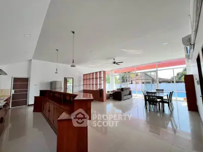 Spacious open-plan living room with modern kitchen and dining area, featuring high ceilings and ample natural light.