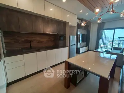 Modern open-plan kitchen with sleek cabinetry and stylish lighting in a high-rise apartment.