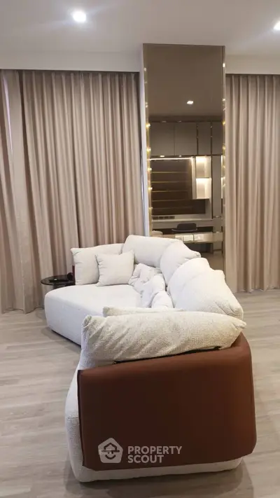 Luxurious modern living room with elegant sofa and floor-to-ceiling curtains.