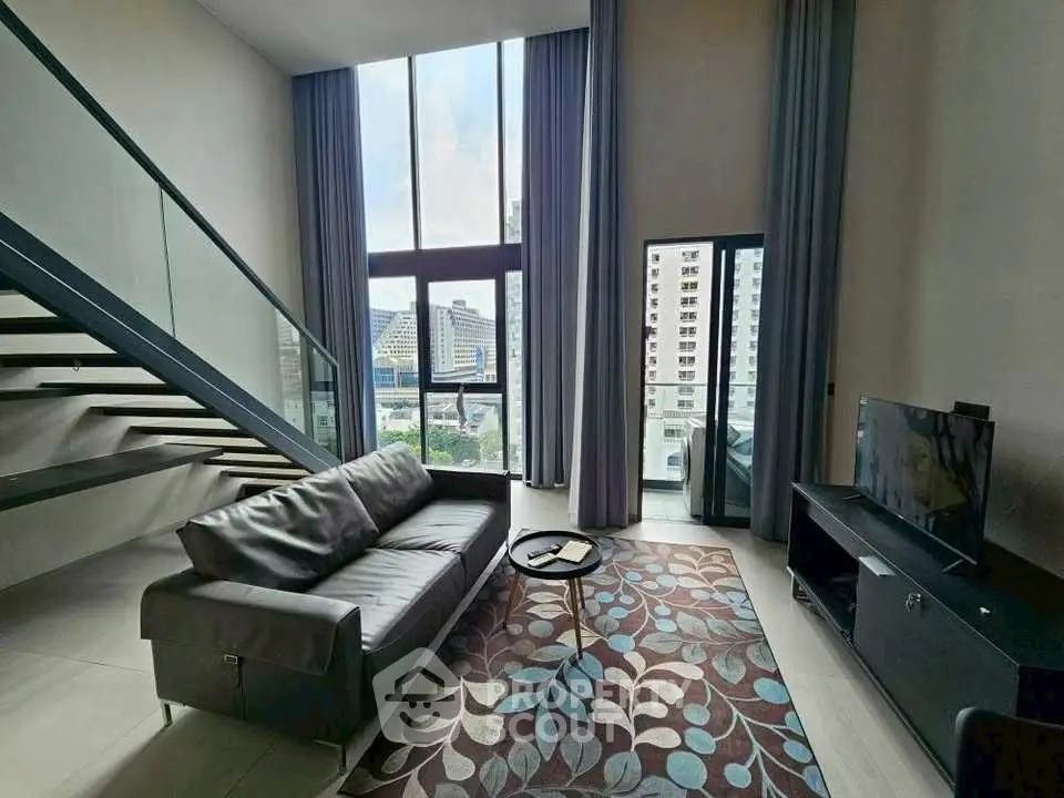 Modern living room with high ceilings and city view, featuring a sleek staircase and stylish decor.