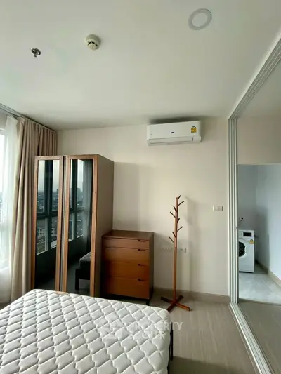 Modern bedroom with city view, featuring a mirrored wardrobe and air conditioning.